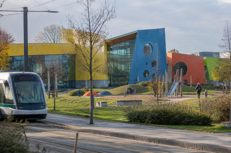 The bright modern building of Le Vaisseau children's science centre with a playful outdoor garden, on a clear day