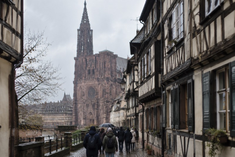 Small group walking past half-timbered houses on a guided tour, seen from behind