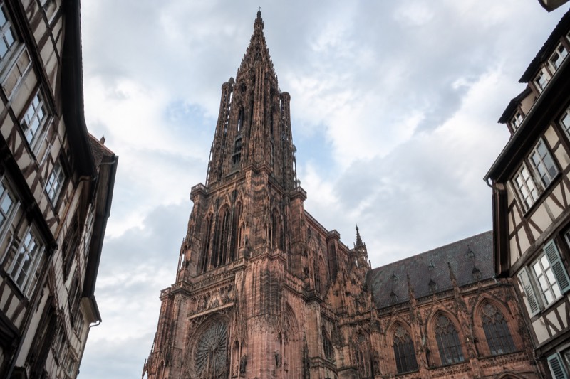 Carved sandstone spire and west front of the cathedral against a pale sky.