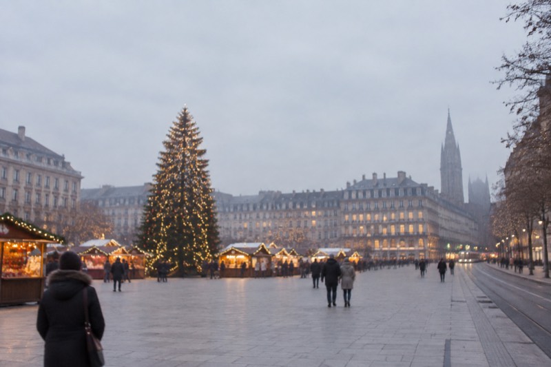 A Christmas-lit Place Kléber with a decorated tree and market stalls, dusk, soft light