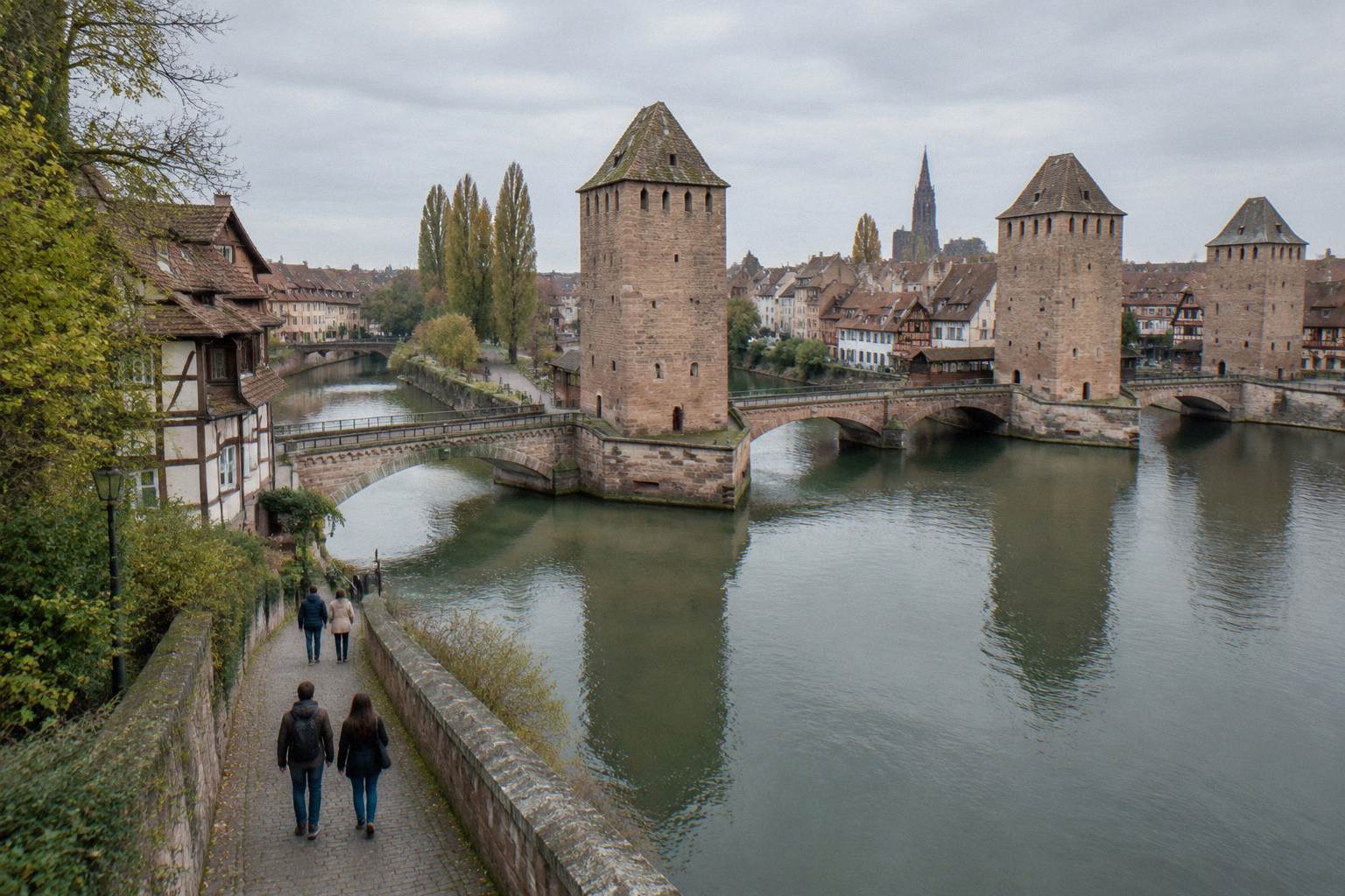 Visitors walking beside the canal toward the covered bridges in Strasbourg