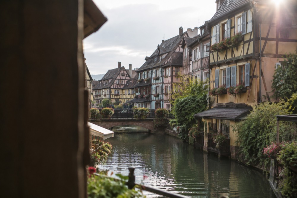 Half-timbered houses along a canal in Colmar's old town on a bright day