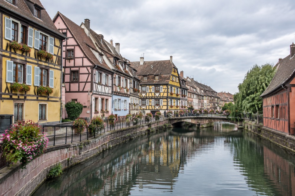 A canal in Colmar's Little Venice district reflecting coloured half-timbered houses