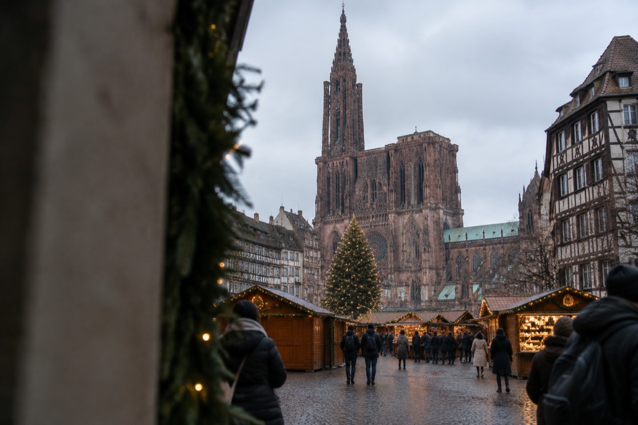 Christmas market chalets and a decorated tree in a floodlit square in Strasbourg at dusk