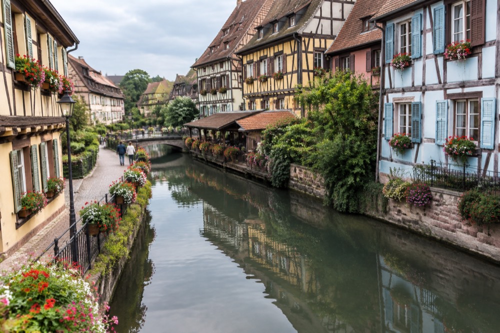 Flower-decked facades reflected in one of Colmar's canals