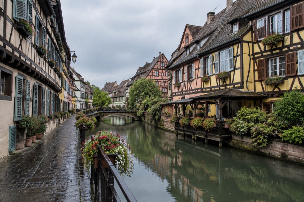 A quiet side street in Colmar with timber-framed houses and shutters, empty of visitors