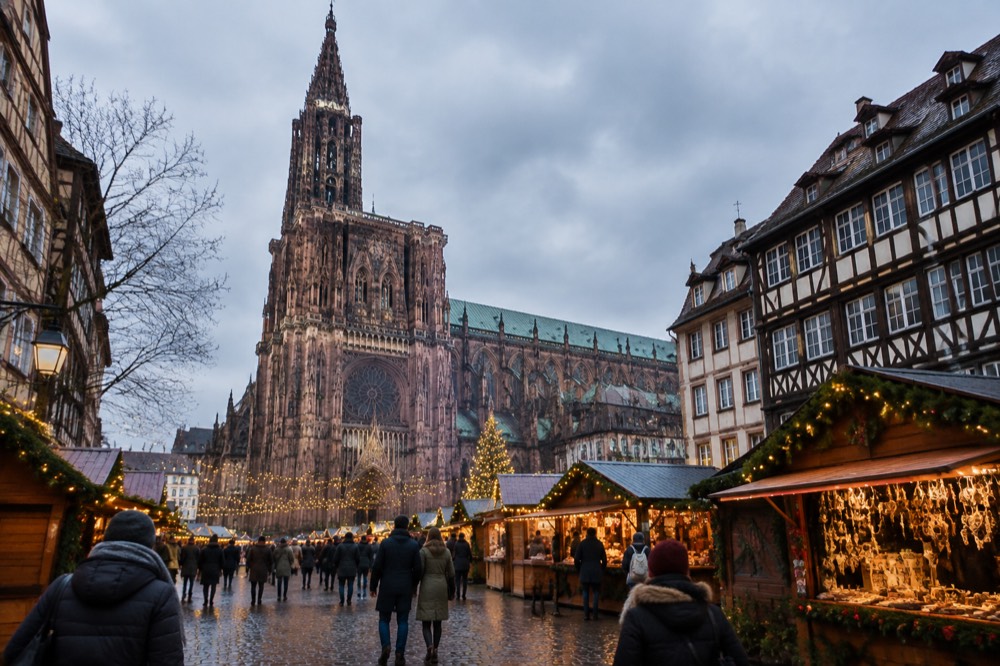 Christmas market chalets and strings of lights along a Strasbourg square in the early evening