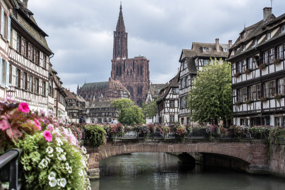 Flower-decked bridge over a canal with timber-framed buildings in a Strasbourg old town street