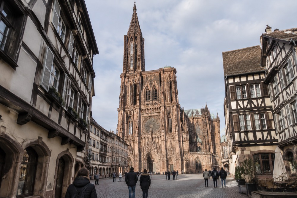Gothic cathedral facade with a single openwork spire rising above a medieval square