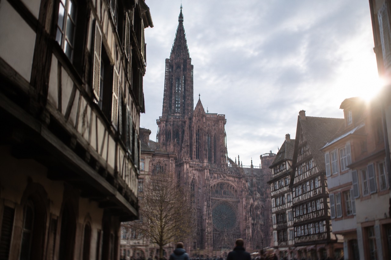 Gothic cathedral facade with a single openwork spire rising above a medieval square