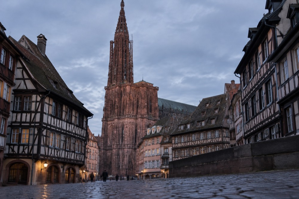 The pink sandstone west front of Strasbourg Cathedral rising above rooftops on a clear morning