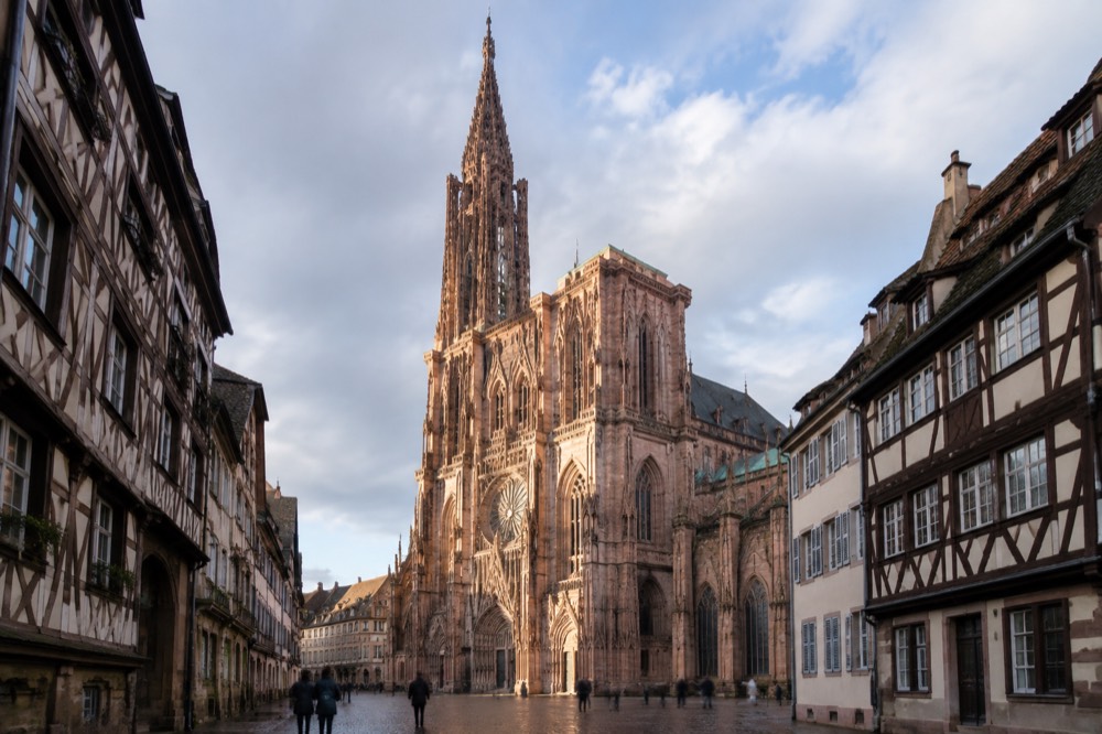 Sunlight falling across the Gothic columns and rose window inside Strasbourg Cathedral's nave