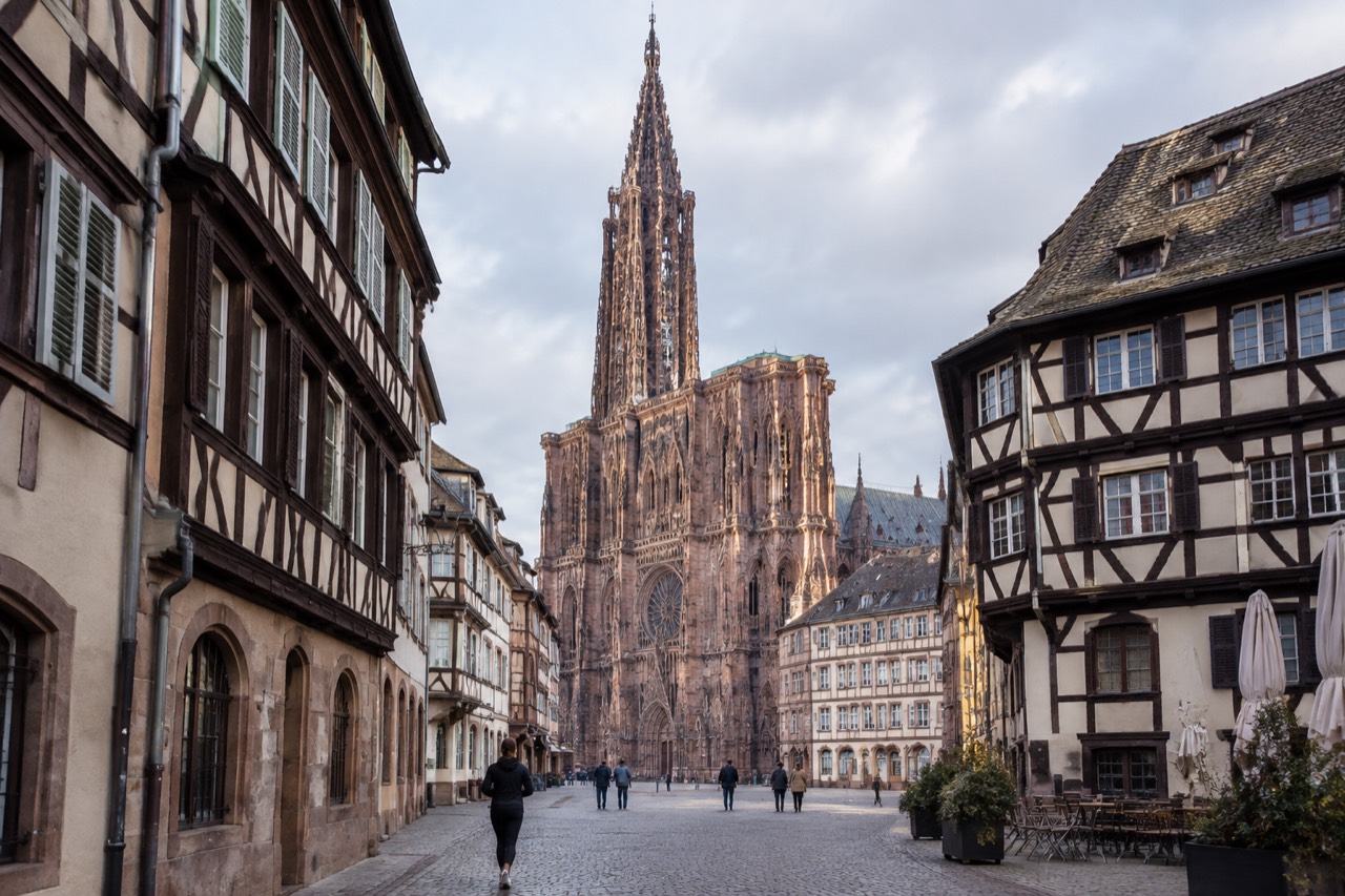The pink sandstone west front of Strasbourg Cathedral rising above rooftops on a clear morning