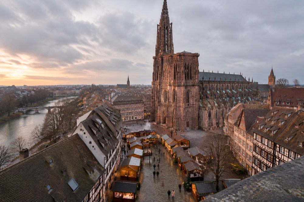 Wooden market chalets with warm lights along a cobbled square in evening