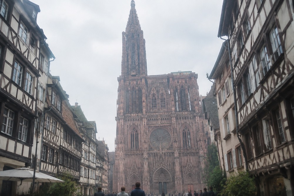 The pink sandstone west front of Strasbourg Cathedral seen from a square below