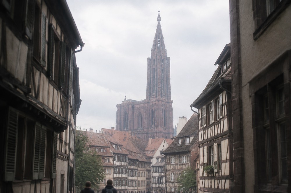 The single spire of Strasbourg Cathedral seen above red-tiled rooftops of the old town