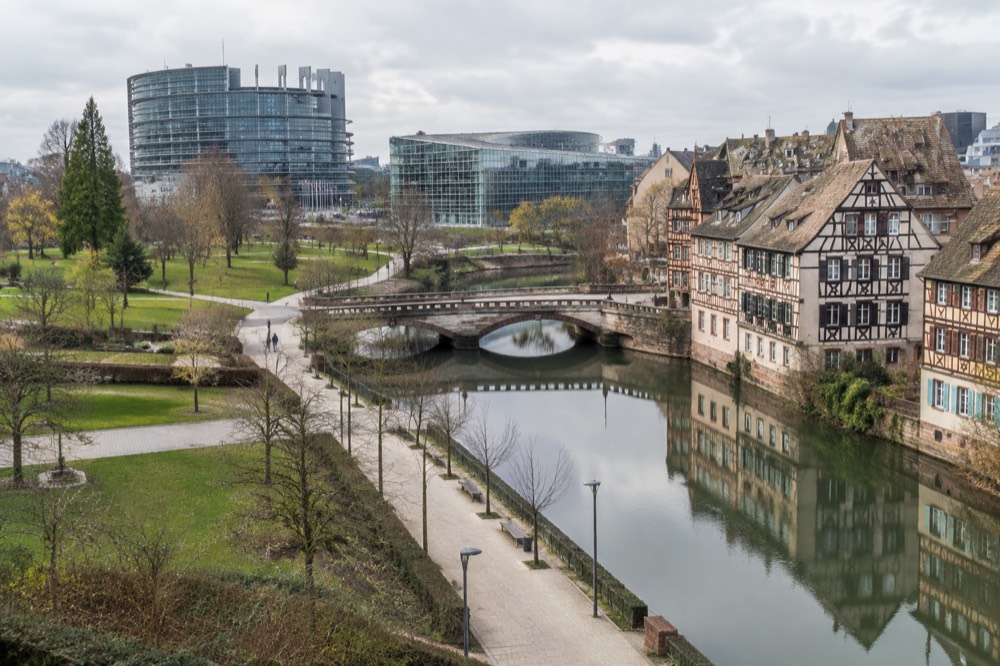 Half-timbered houses reflected in a calm river channel beside a stone bridge in an old European quarter