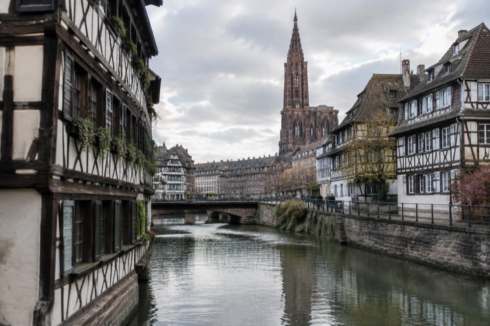 Half-timbered houses along a canal in Petite France, Strasbourg, with the cathedral spire in the background