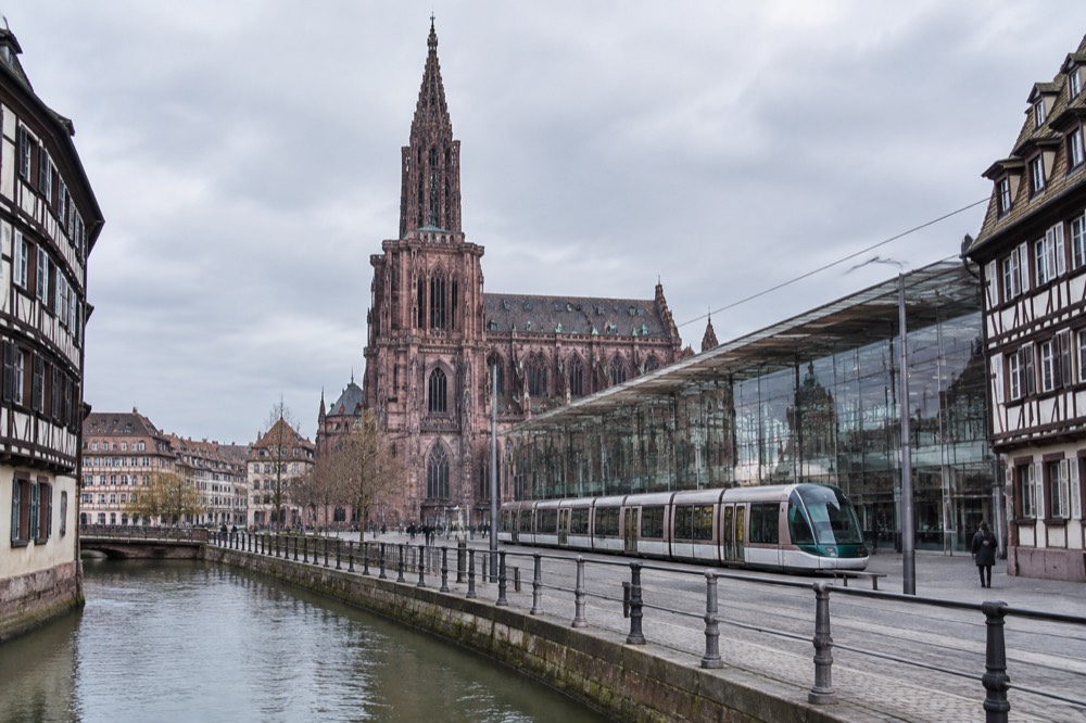 The glass facade of Strasbourg central station with trams passing in front