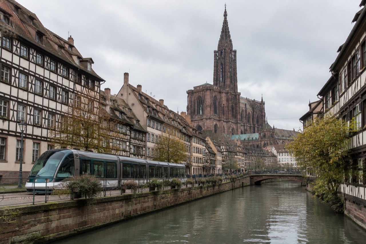 A tram passing half-timbered buildings along a canal in central Strasbourg