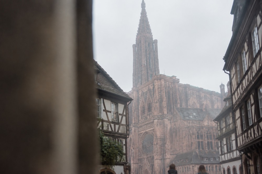 The pink sandstone facade of Strasbourg Cathedral seen from a narrow street in the old town