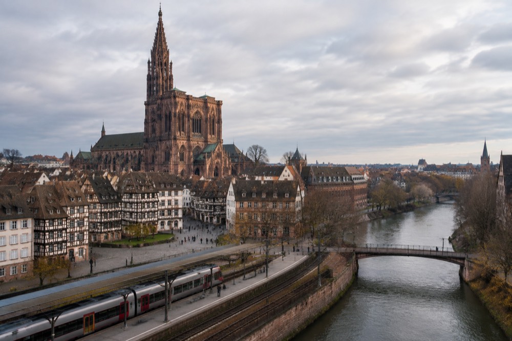 A regional train waiting at a platform with the Strasbourg skyline behind it