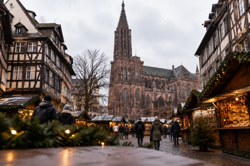 Christmas market chalets and garlands in a Strasbourg square with the cathedral rising behind
