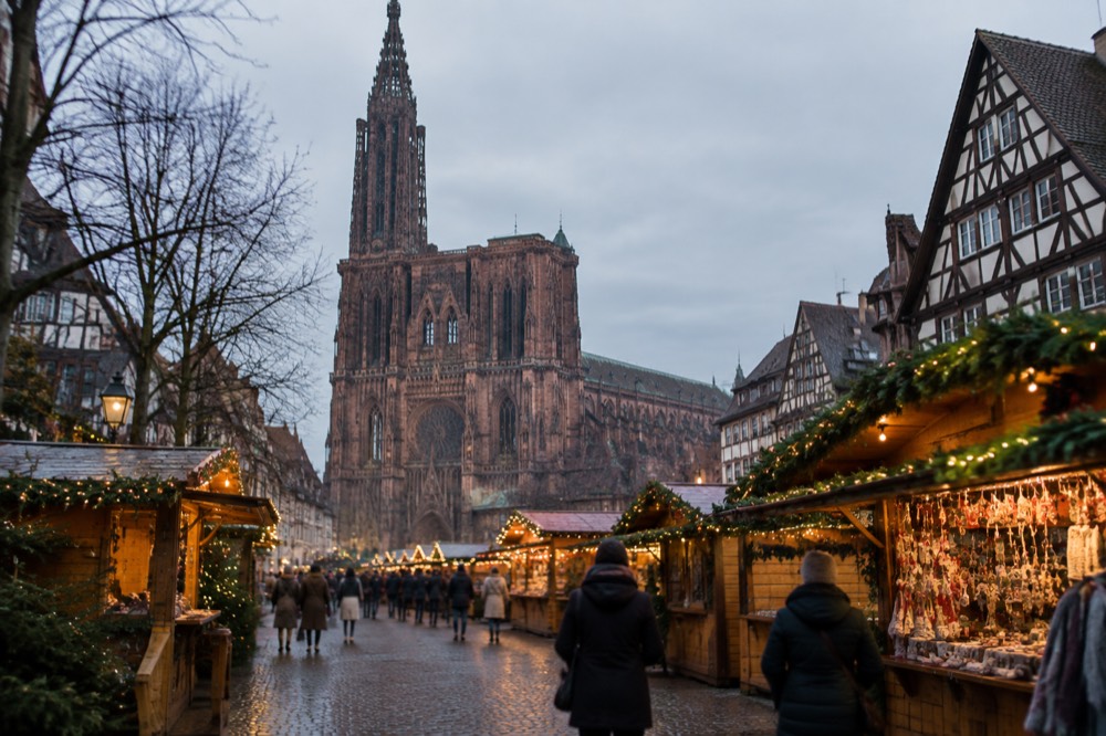 Christmas market chalets with festive lights in a Strasbourg square at dusk