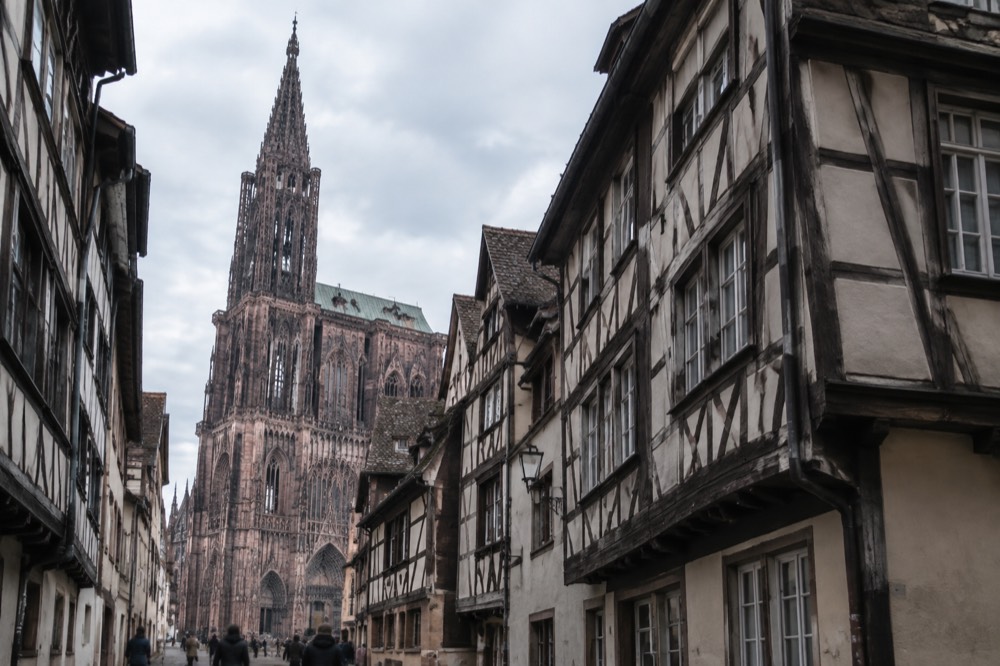 Cathedral tower seen from a narrow street of half-timbered houses in Strasbourg
