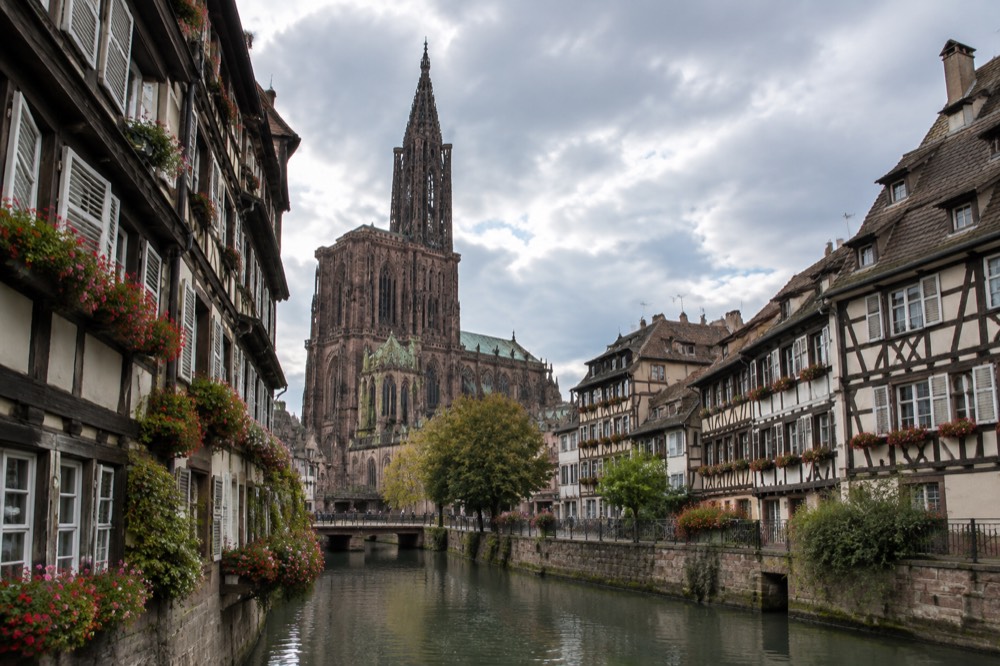 Half-timbered houses along a Strasbourg canal with flowers on the balconies