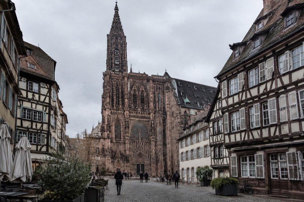 A historic Strasbourg square with timber-framed facades under a grey sky
