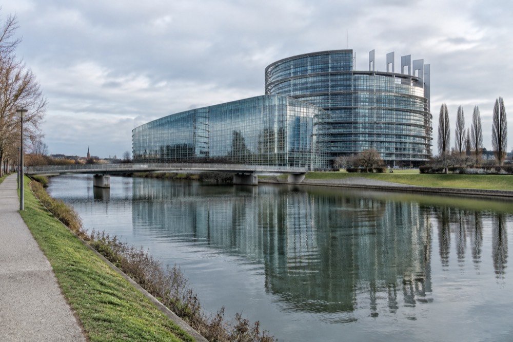 Glass façade of the European Parliament building reflected in the River Ill
