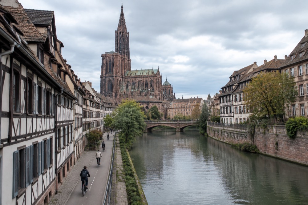 Cyclists riding a dedicated bike lane along a canal in central Strasbourg