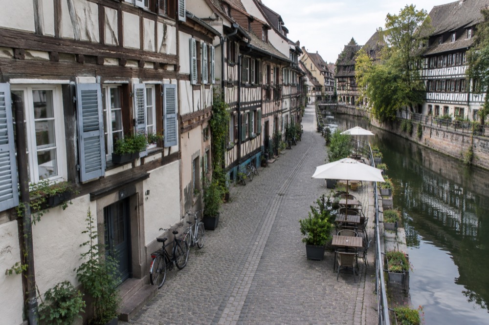 A narrow lane of half-timbered houses with bicycles leaning against a wall in the Krutenau