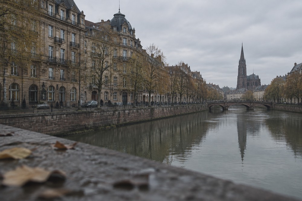 Church with a tall spire reflected in the Ill river