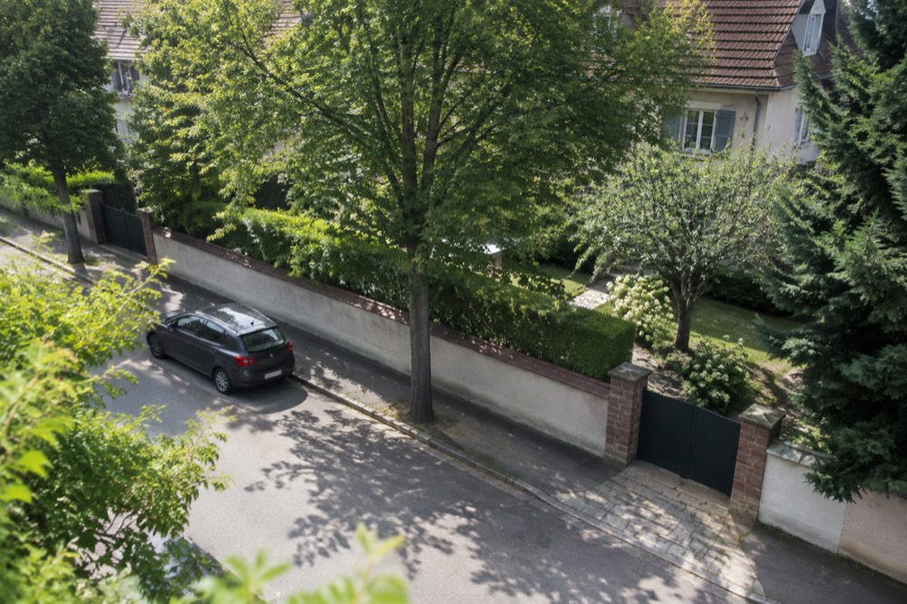 Garden wall and mature trees on a quiet residential street in Robertsau, Strasbourg