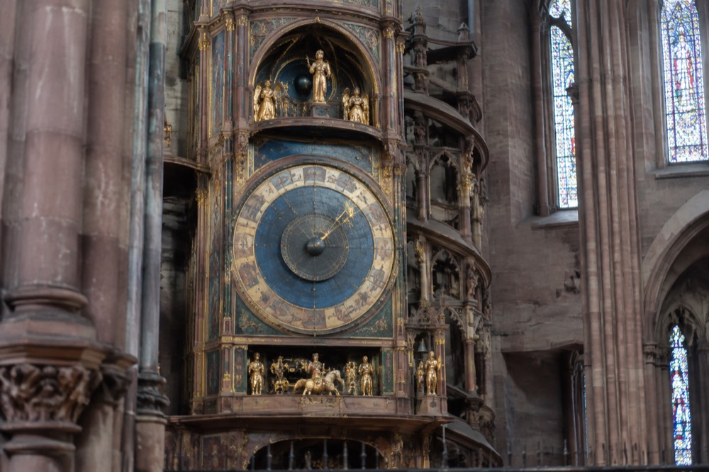 The ornate astronomical clock inside Strasbourg Cathedral, with its painted dials and golden automaton figures lit by daylight
