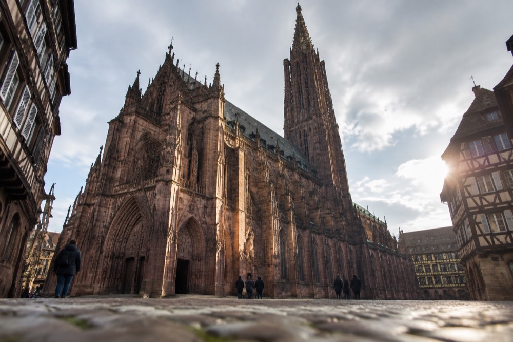 The tall Gothic nave of Strasbourg Cathedral seen from the west entrance, with light striking the columns