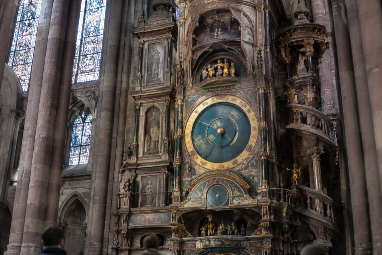 The ornate astronomical clock inside Strasbourg Cathedral, with its painted dials and golden automaton figures lit by daylight