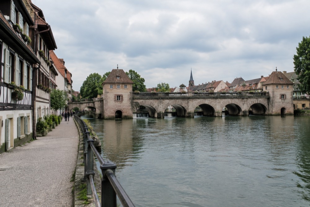 Half-timbered houses beside a canal with a walking path along the water