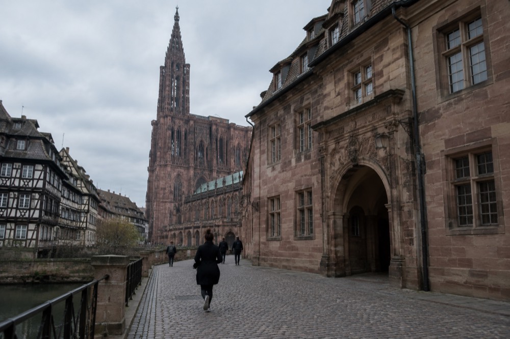 Historic stone hospital building with arched entrance in central Strasbourg