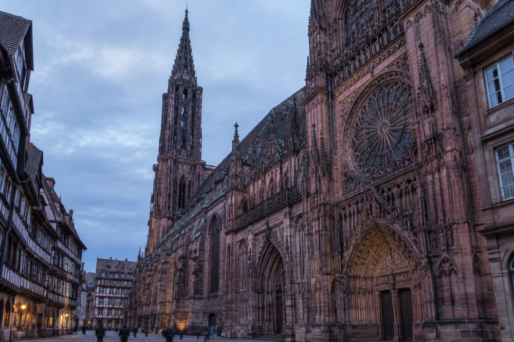 Close view of carved stone detail and a rose window on a church facade in Strasbourg