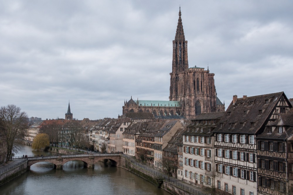 Evening view of a floodlit church tower above Strasbourg rooftops