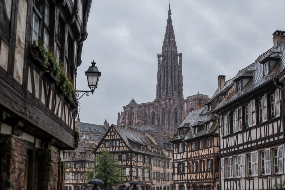 The single spire of Strasbourg Cathedral seen above old-town rooftops near the church