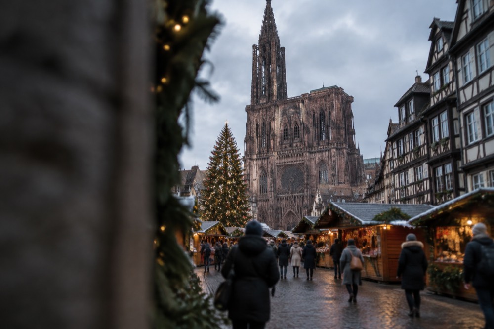 Christmas market chalets and a decorated tree in a Strasbourg square at dusk