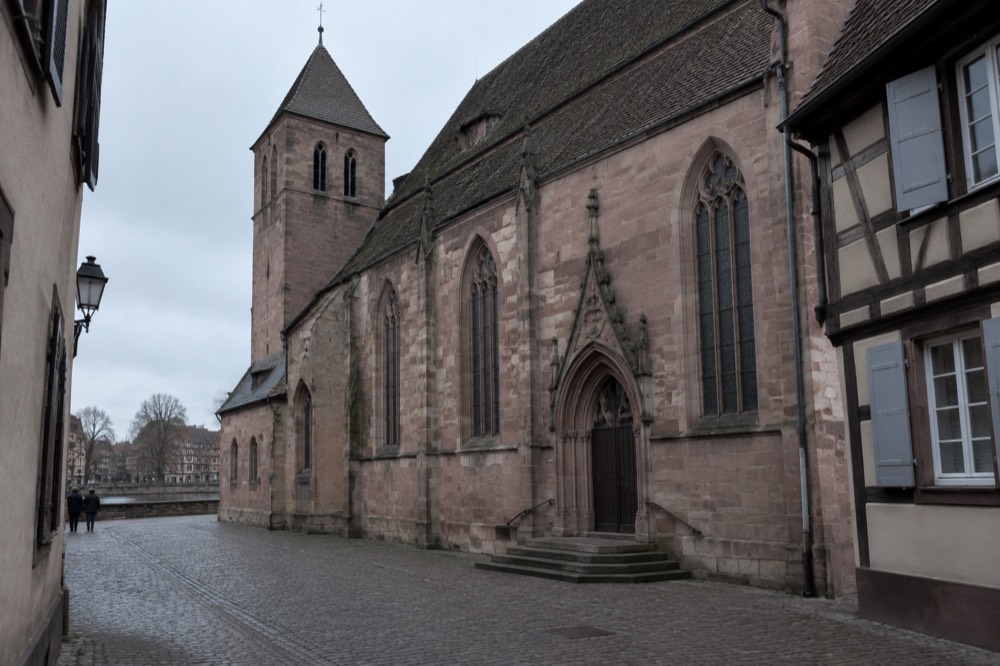 The exterior wall and entrance of the Église Saint-Pierre-Le-Jeune seen from a narrow street