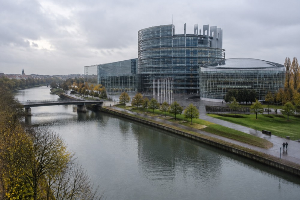 The European Parliament building beside the River Ill in Strasbourg with its curved glass facade under a wide sky