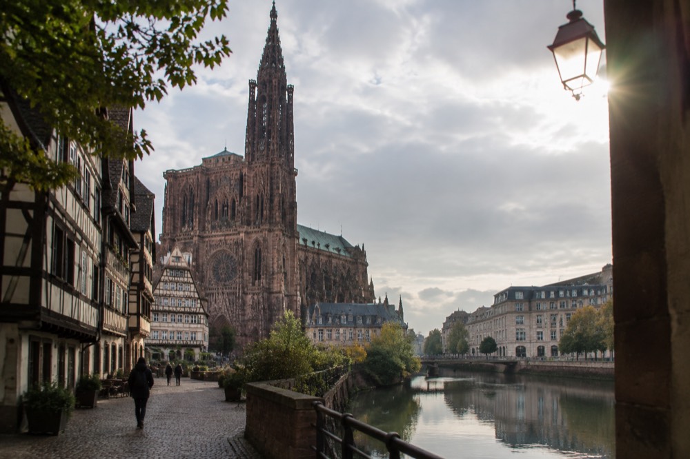 Modern institutional buildings reflected in calm water along the River Ill in Strasbourg