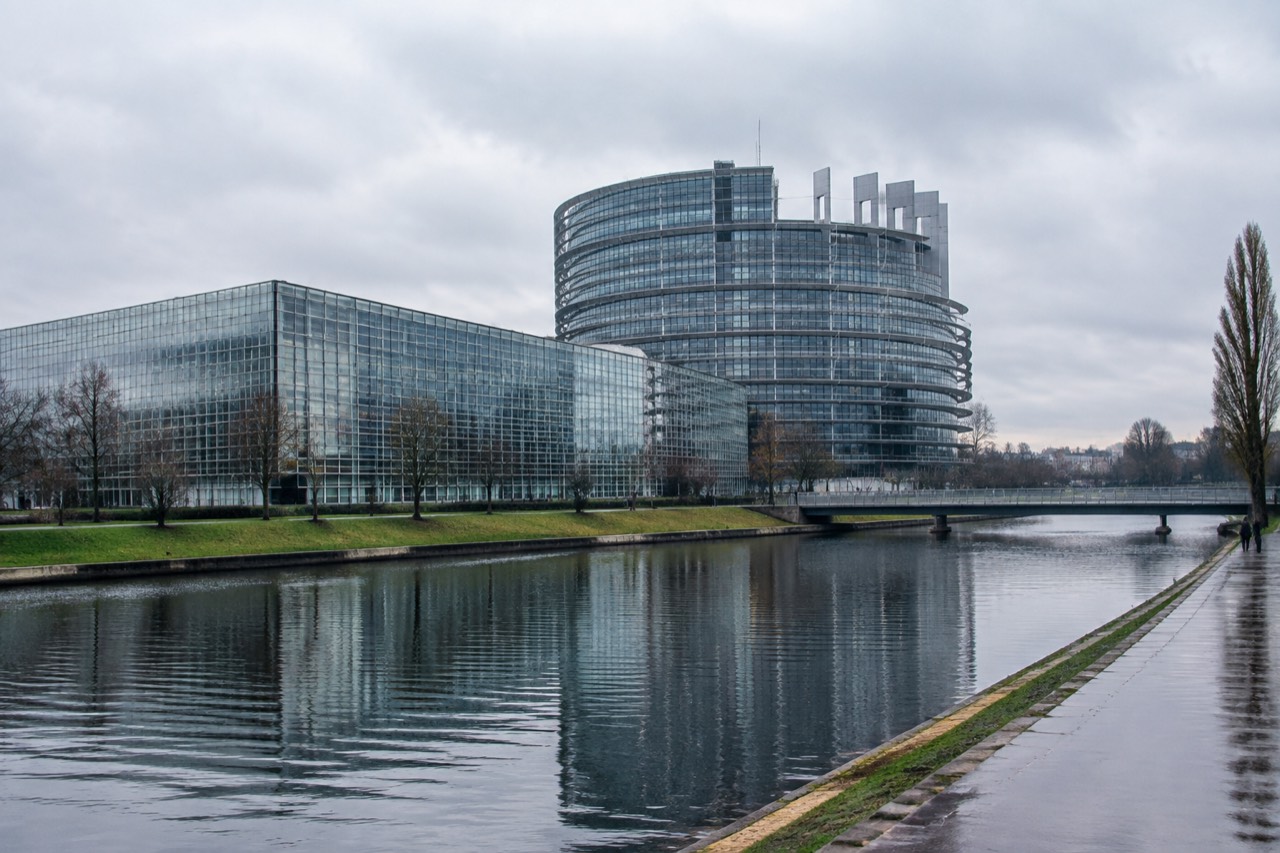 The European Parliament building beside the water in Strasbourg with its glass and steel facade reflecting the sky