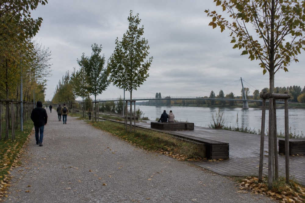Wide gravel paths and young trees in the cross-border park in early autumn